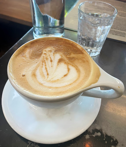A vegan cappuccino with latte art on a steel table