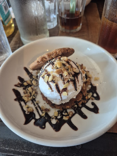 A brownie sundae with chocolate drizzle and toasted hazelnuts