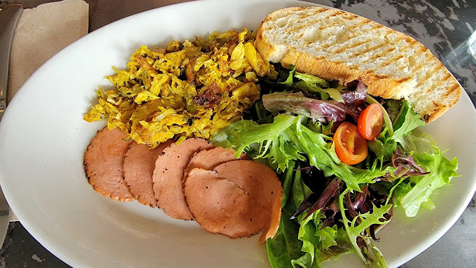 A plant-based breakfast plate: turmeric scramble, vegan ham, sourdough, mixed greens