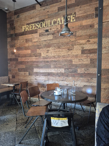 Freesoulcaffé's reclaimed wood wall, stenciled in gold, beside a round marble table